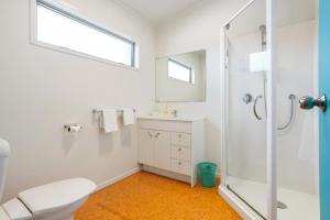 a white bathroom with a shower and a toilet at Ocean Road Beach House in Whangamata +12 photos