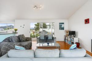 a living room with two couches and a table at Ocean Road Beach House in Whangamata