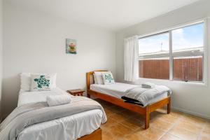a bedroom with two beds and a window at Ocean Road Beach House in Whangamata