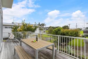 a deck with a wooden table and bench on a balcony at Ocean Road Beach House in Whangamata
