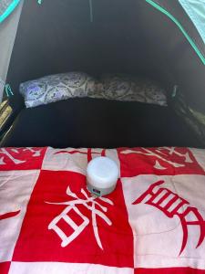 a bed in a tent with a red and white blanket at Camping Místico - Vale do Ribeira in Juquiá