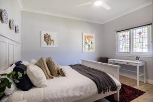 a white bedroom with a bed with pillows at Ivy Cottage Milton in Milton