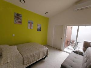 a bedroom with green walls and a bed and a couch at Villa Del Mar 14 in Antón Lizardo