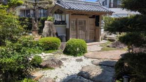 a japanese garden with a gate in front of a house at くまの蔵 Kumanokura inn Storehouse in Shingū
