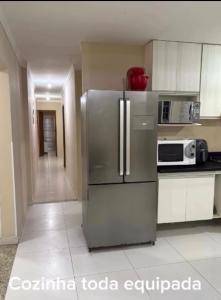 a kitchen with a stainless steel refrigerator and microwave at Ice pool house in São Vicente