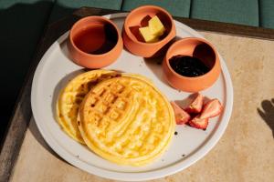 a plate with waffles and some syrup and some fruit at The Cut Hotel in Medellín