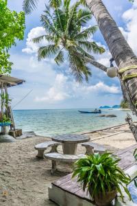 a picnic table on the beach with a palm tree at Two Rocks Bungalows in Baan Tai