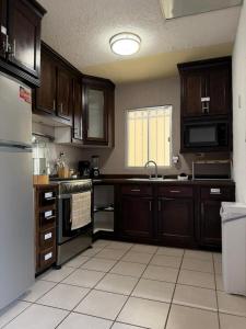 a kitchen with wooden cabinets and a white tile floor at Casa privada con estacionamiento in Hermosillo