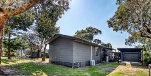 a small shed in a yard with trees at The Deck @ VB - Linen, Wi-Fi, Pets, Secured Yard in Venus Bay