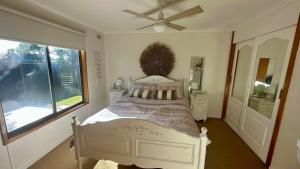 a bedroom with a bed with a fan and a window at The Deck @ VB - Linen, Wi-Fi, Pets, Secured Yard in Venus Bay