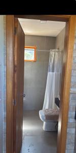 a bathroom with a toilet and a shower curtain at Chalé Corumbau - Lapinha da Serra in Santana do Riacho +22 photos
