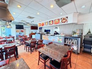 a restaurant with tables and chairs and a person in the kitchen at Hometel Suites in Los Angeles