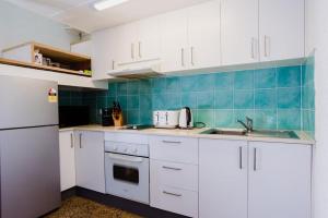 a kitchen with white cabinets and a blue tiled wall at Binishell Igloo 6 - Famous Beachfront Dome with Pool in Trinity Beach