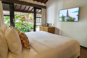 a bedroom with a large white bed and a window at Goya Courtyard Ubud in Ubud