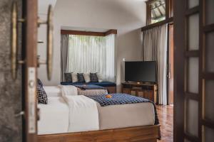 a living room with two beds and a flat screen tv at Asvara Villa Ubud by Ini Vie Hospitality in Ubud