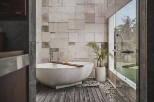 a bathroom with a tub and a potted plant at Asvara Villa Ubud by Ini Vie Hospitality in Ubud