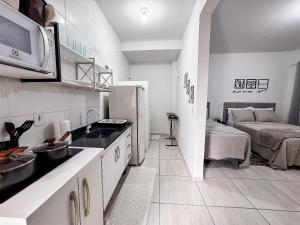 a kitchen with a sink and a refrigerator and a bed at Apê completo p/ 3 • vaga + Wi-Fi in Brusque +14 photos
