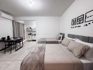 a bedroom with two beds and a dining table at Apê completo p/ 3 • vaga + Wi-Fi in Brusque