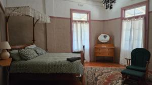 a bedroom with a bed and a chair and a mirror at Hotel Shakespeare Barcaldine in Barcaldine