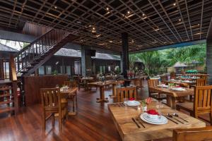 een restaurant met houten tafels en houten stoelen bij Coconut Boutique Resort in Senggigi 