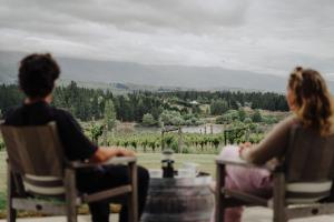 two people sitting at a table looking out at a vineyard at The Retreat at Carrick Vineyard in Cromwell