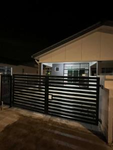 a fence in front of a house at night at Nady's Homestay in Banting