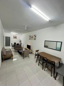 a living room with tables and chairs and a flat screen tv at Nady's Homestay in Banting