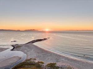 a sunset over the ocean with a sandy beach at Shepherd's Cottage at Lisdillon Estate in Little Swanport
