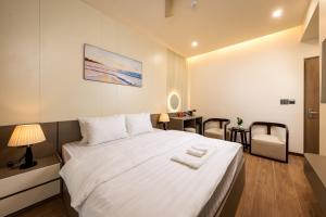 a bedroom with a large white bed and a desk at Cyan Sầm Sơn Hotel in Sầm Sơn