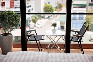 a room with two chairs and a table in front of a window at Cyan Sầm Sơn Hotel in Sầm Sơn