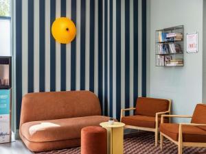 a living room with a chair and a yellow mirror at Aparthotel Adagio Access Toulouse Jolimont in Toulouse