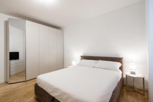 a white bedroom with a large bed and a mirror at Alla Loggia in Udine
