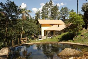 a house with a pond in front of it at Serra Nevada House in Nova Friburgo