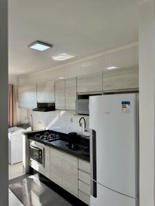 a kitchen with white appliances and a white refrigerator at Apartamento 2 Quartos Aconchegante - Ar Condicionado nos Quartos - 1 Cama Casal - 2 Camas de Solteiro com Auxiliar - Cozinha Completa - Estacionamento Gratuito in Três Lagoas