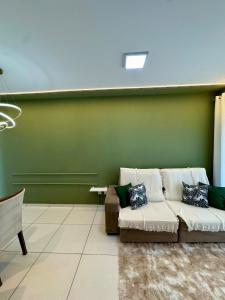 a living room with a couch and a green wall at Apartamento 2 Quartos Aconchegante - Ar Condicionado nos Quartos - 1 Cama Casal - 2 Camas de Solteiro com Auxiliar - Cozinha Completa - Estacionamento Gratuito in Três Lagoas +12 photos