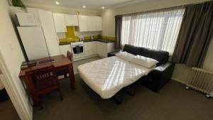 a room with a bed and a table and a kitchen at Crow's Nest in Picton