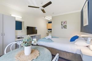 a bedroom with a bed and a table at Ocean Parade Motel in Coffs Harbour