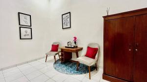 a room with a desk and two chairs and a cabinet at Suite Room The Megatruh in Kejayan