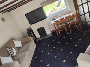 a living room with a couch and a table and a television at Tudor Cottage, Newby Bridge in Ulverston