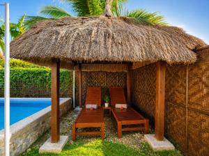 a hut with chairs and a table next to a pool at Villas Flora Bella Sunflower in Dauis