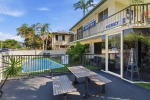 a hotel with a bench next to a swimming pool at Ocean Parade Motel in Coffs Harbour