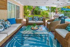 a patio with wicker furniture and a glass coffee table at Trinity Charm - Beachside Family Getaway with Pool in Trinity Beach