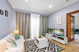 a living room with a white couch and a tv at Trinity Charm - Beachside Family Getaway with Pool in Trinity Beach