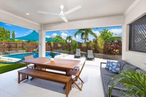a patio with a wooden table and chairs and a pool at Tropical Dreams - Spacious Retreat with Private Pool in Smithfield