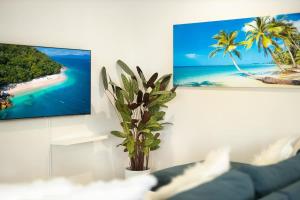 a living room with a couch and a tv on a wall at Tropical Dreams - Spacious Retreat with Private Pool in Smithfield