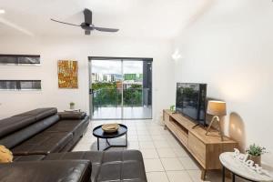 a living room with a couch and a tv at Panorama Cairns - City & Coastal Views with Pool in Cairns