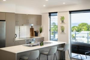 a kitchen with a sink and a counter with chairs at Panorama Cairns - City & Coastal Views with Pool in Cairns +18 photos