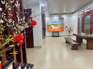 a living room with a tv and a couch and flowers at Cong Hoa Homestay in Vũ Lâm