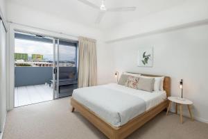 a white bedroom with a bed and a balcony at Panorama Cairns - City & Coastal Views with Pool in Cairns