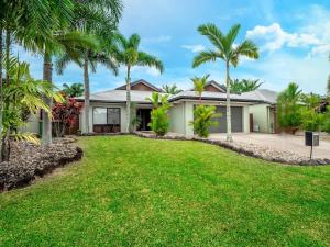 a house with palm trees in front of it at Tropical Pool Sanctuary in Kewarra Beach, Family and Dog Friendly in Kewarra Beach